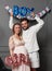 Amused couple holding up inscription boy or girl during gender reveals party, over balloons.