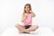 Amused cute lively blond little girl enjoy playing smartphone, resting download awesome game, pointing finger camera