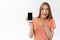 Amused, excited good-looking woman in striped t-shirt, smiling enthusiastic, holding smartphone pointing mobile screen