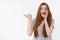 Amused happy cheerful surprised young cute redhead girl blue eyes drop jaw pointing left thumb excited standing