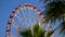 Amusement park ferris wheel slowly turning against blue sky