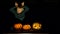 Amusing child playing as vampire close illuminated pumpkins, funniest Halloween video, dark background