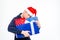 Amusing cute man in santa claus hat hugging gift boxes