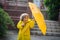 The amusing little boy in a yellow raincoat and with umbrella stand at rain.