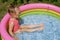 A amusing little girl in a pink swimsuit and sunglasses splashes in the water in an inflatable small rubber swimming  pool