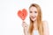 Amusing woman showing tongue and holding heart shaper lollipop