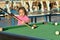 Amusing yong girl playing billiards