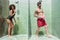 Amusing young couple entertaining simultaneously in near-by shower cubicles