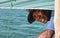 Anakao, Madagascar - May 03, 2019: Unknown Malagasy fisherman looking back under main green sail of his piroga small fishing boat