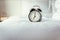 Analog Alarm Clock on Bedroom in Modern House, Retro Timer at 7.00 a.m. on White Cover Bed