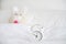 Analog  clock and blurred cute little rabbit doll lying alone on white bed for wake up or go to bed, well sleeping, sweet