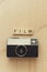 Analog film camera on wooden surface. Film word in capital letters