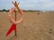 Anapa, Russia, August 10, 2021 Lifebuoy with a red flag on a sandy beach. Orange lifebuoy on a pole to rescue people