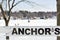 Anchor`s Sign in Front of Lake with Ice Fishermen