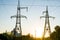 Anchor supports with high-voltage wires on the background of the plant and the sunset