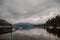 The anchor yacht in harbor near pier  After rain cloudy sky, misty forest mountains and calm water.