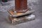 Anchoring of a rusty iron pillar to old concrete foundation with huge steel nuts and bolts