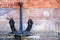 Ancient anchor stands on the ground leaning against the wall