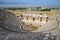 Ancient antique amphitheater in city of Hierapolis in Turkey. Steps and antique statues with columns in the amphitheater