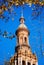 Ancient architecture tower view in Plaza de EspaÃ±a against blue sunny clear sky framed by tree leaves. Main landmark popular