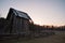 Ancient barn of wood, surrounded by a fence at dawn,