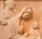 Ancient bas-relief depicting young seated woman with boy and maiden stands in background on ancient Greek funerary stele from