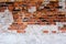 Ancient brick wall with plaster made of red-orange brick. Shattered surface. An abandoned house or an old factory.