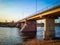 Ancient bridge over the river with stone pillars. Rapid flow of water in spring. Sunset view.