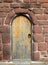 Ancient brown wooden door in a red sandstone medieval wall