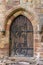 An ancient brown wooden door with unusual hinges