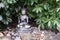 Ancient Buddha sculpture seated among lush green foliage