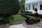 Ancient cannon and sculpture of lion, near the steps of the house. Beautifully trimmed bushes. Garden sculpture