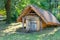 An ancient clay cellar with a thatched roof in the summer garden of a rural estate