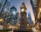 Ancient clock tower stands majestic amidst modern skyscrapers in a bustling city