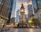 Ancient clock tower stands majestic amidst modern skyscrapers in a bustling city