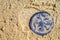 Ancient copper coin with a double-headed eagle covered with sand lying on the sand