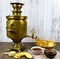 Ancient copper samovar on a wooden table with a Cup of tea breadcrumbs biscuits jam.