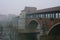 Ancient covered bridge surrounded by fog in winter. Pavia. Italy