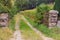 Ancient damaged gate with trail to the forest. Old stone fence and iron gate near corn field. Walk in abandoned places, France.