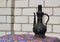 Ancient eastern brass water jar on white brick wall background