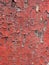 Ancient faded cracked peeling red paint forming an abstract pattern on a flat concrete surface
