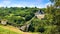 An ancient fortress wall with a watchtower on the hills overgrown with trees and greenery