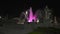 Ancient fountain in Milan illuminated by pink neon lights