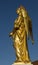 Ancient golden sculpture of angel at the background of blue sky