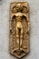 Ancient golden statuette in the shape of mythic humanoid. Old alien figurine on the wall with strange and mysterious symbols. Clay