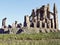 Ancient gothic stone architecture ruins with gargoyle statues in an open field.