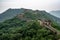 Ancient Great Wall of China between trees, surrounded with green plants