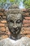Ancient head of Buddha statue in the sun, Thailand