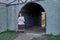 An ancient house and a woman in a vintage dress next to an archway leading to a courtyard