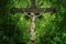 Ancient iron statue of the crucifixion of Jesus Christ against green background of forest